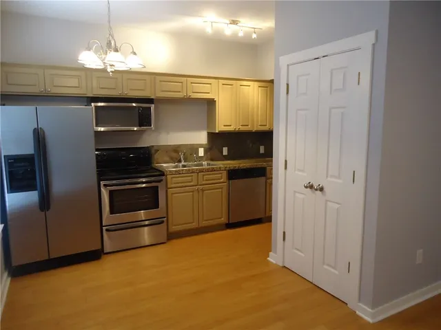 a kitchen with kitchen island granite countertop stainless steel appliances and wooden cabinets