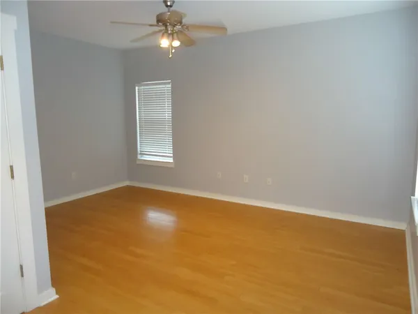 an empty room with a chandelier fan and windows