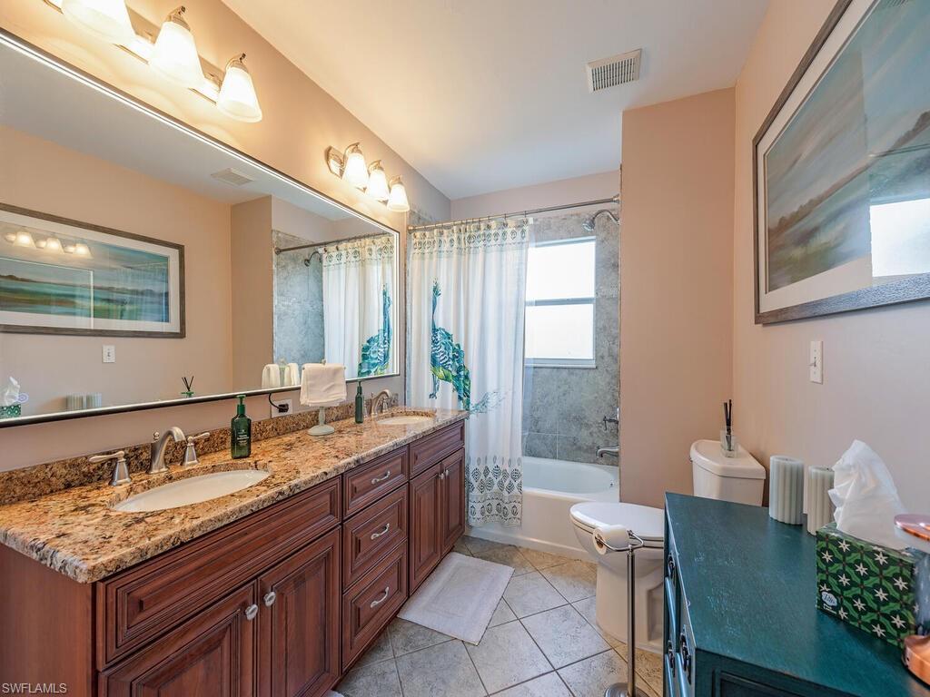 579 Raven Way Naples, FL 34110 - Photo 13 of 19 a bathroom with a granite countertop sink a toilet and large mirror