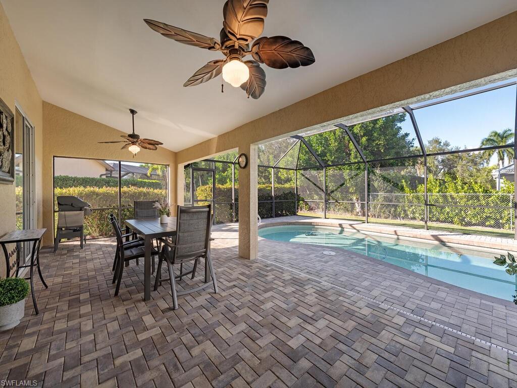 579 Raven Way Naples, FL 34110 - Photo 14 of 19 a dining room with wooden floor a chandelier a flat screen tv and a dining table