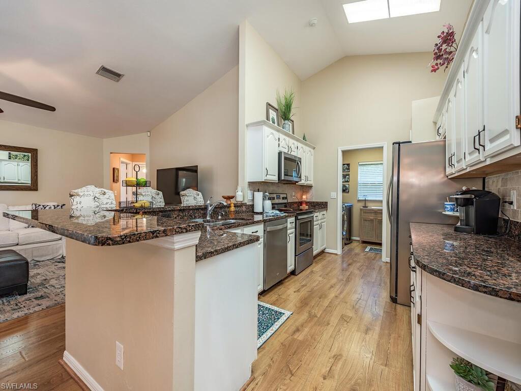 579 Raven Way Naples, FL 34110 - Photo 4 of 19 a kitchen with stainless steel appliances granite countertop a sink stove and refrigerator