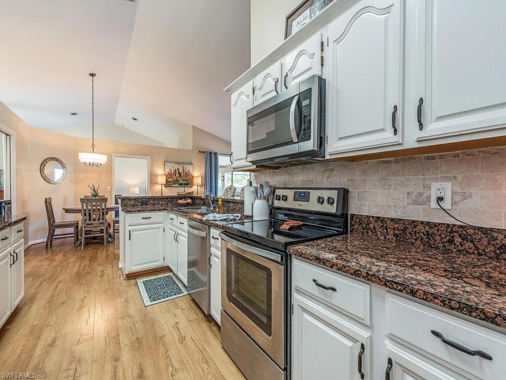 579 Raven Way Naples, FL 34110 - Photo 5 of 19 a kitchen with stainless steel appliances granite countertop a stove a sink and a microwave