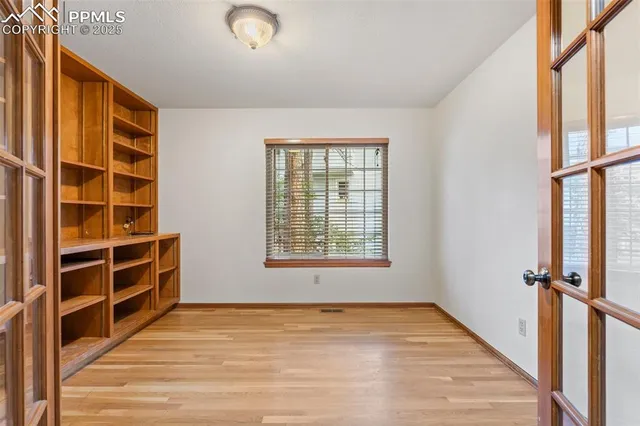 a view of an empty room with a window and wooden floor