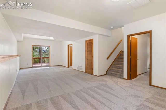 a view of an empty room with wooden floor and stairs