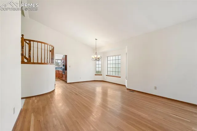 a view of an empty room with window and wooden floor