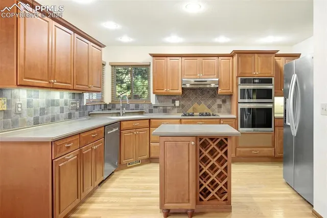 a kitchen with stainless steel appliances granite countertop a stove a sink and a refrigerator