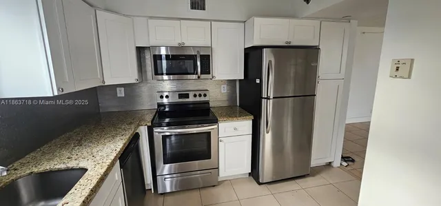 a kitchen with granite countertop a refrigerator and a sink