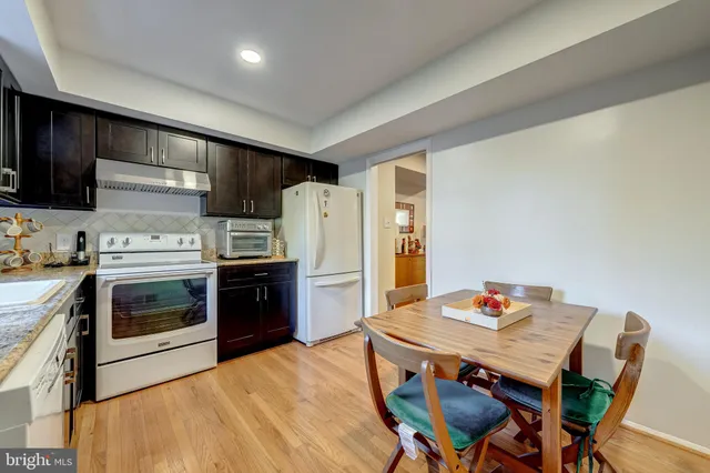 a kitchen with stainless steel appliances kitchen island a table chairs and a refrigerator
