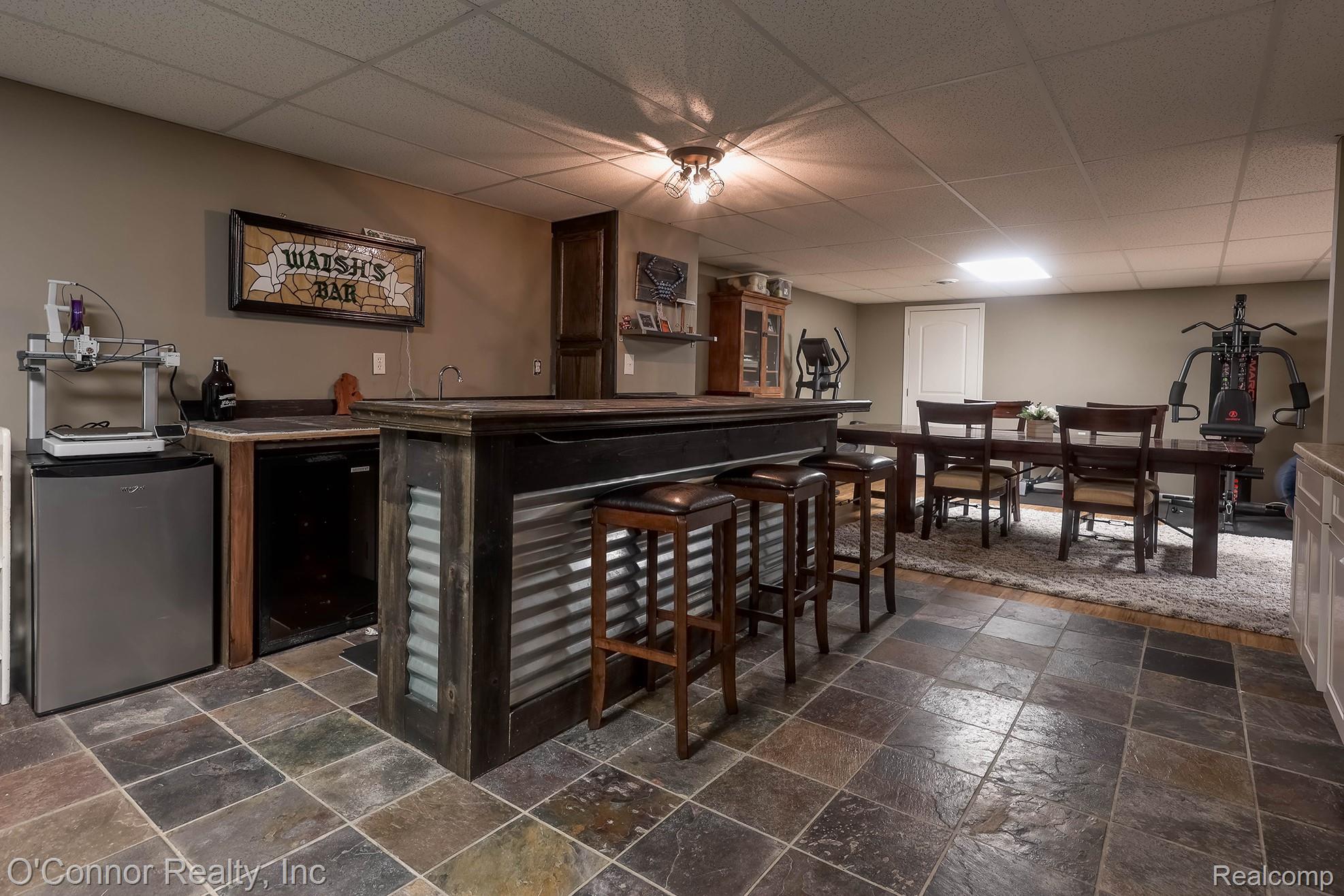 7978 Frith Road Columbus, MI 48063 - Photo 31 of 56 Indoor wet bar with stone tile flooring, a paneled ceiling, black refrigerator, stainless steel fridge, and dark countertops
