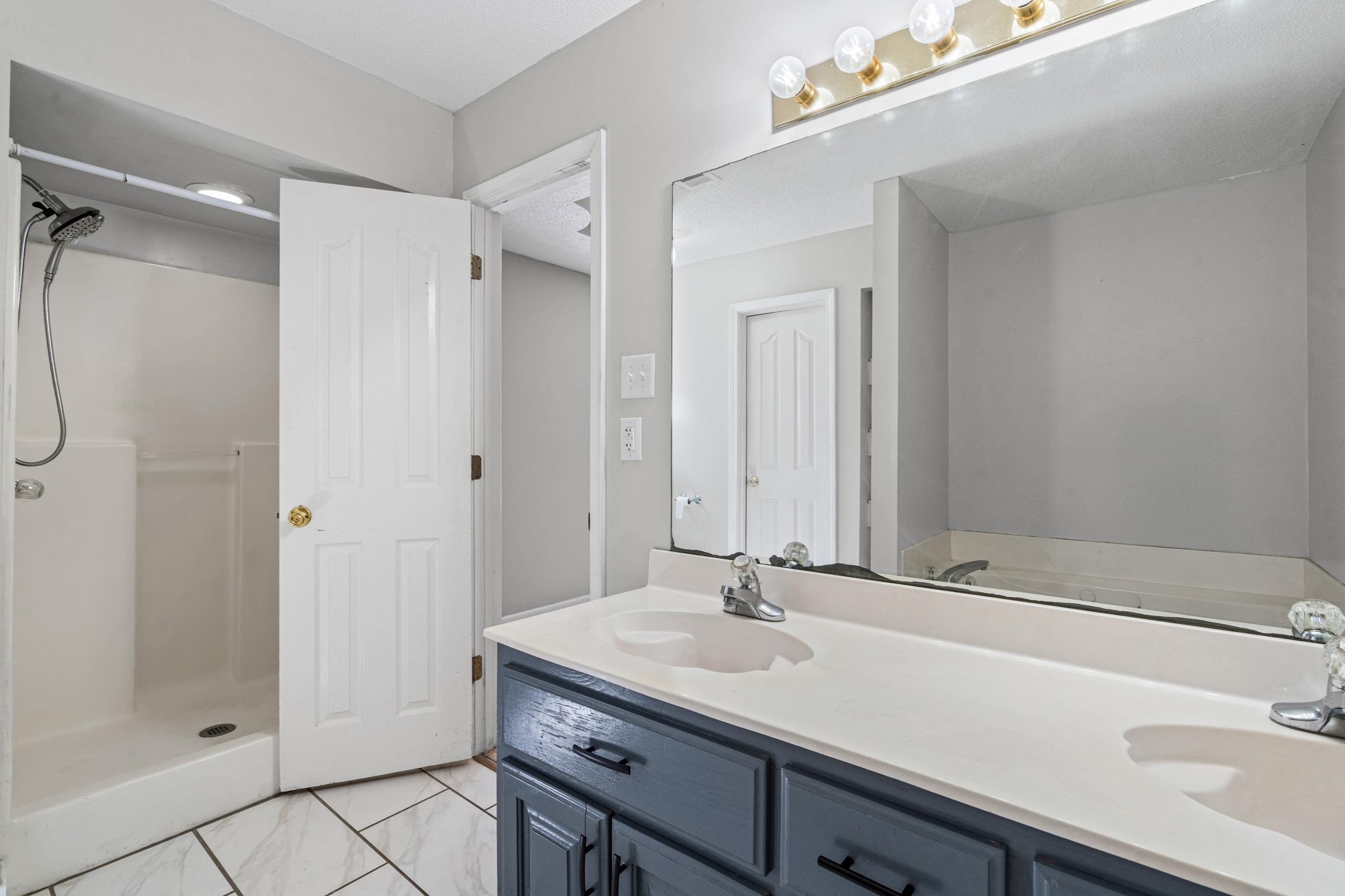 511 Rae Drive Munford, TN 38058 - Photo 12 of 30 Bathroom with double vanity, a stall shower, and light marble finish floors