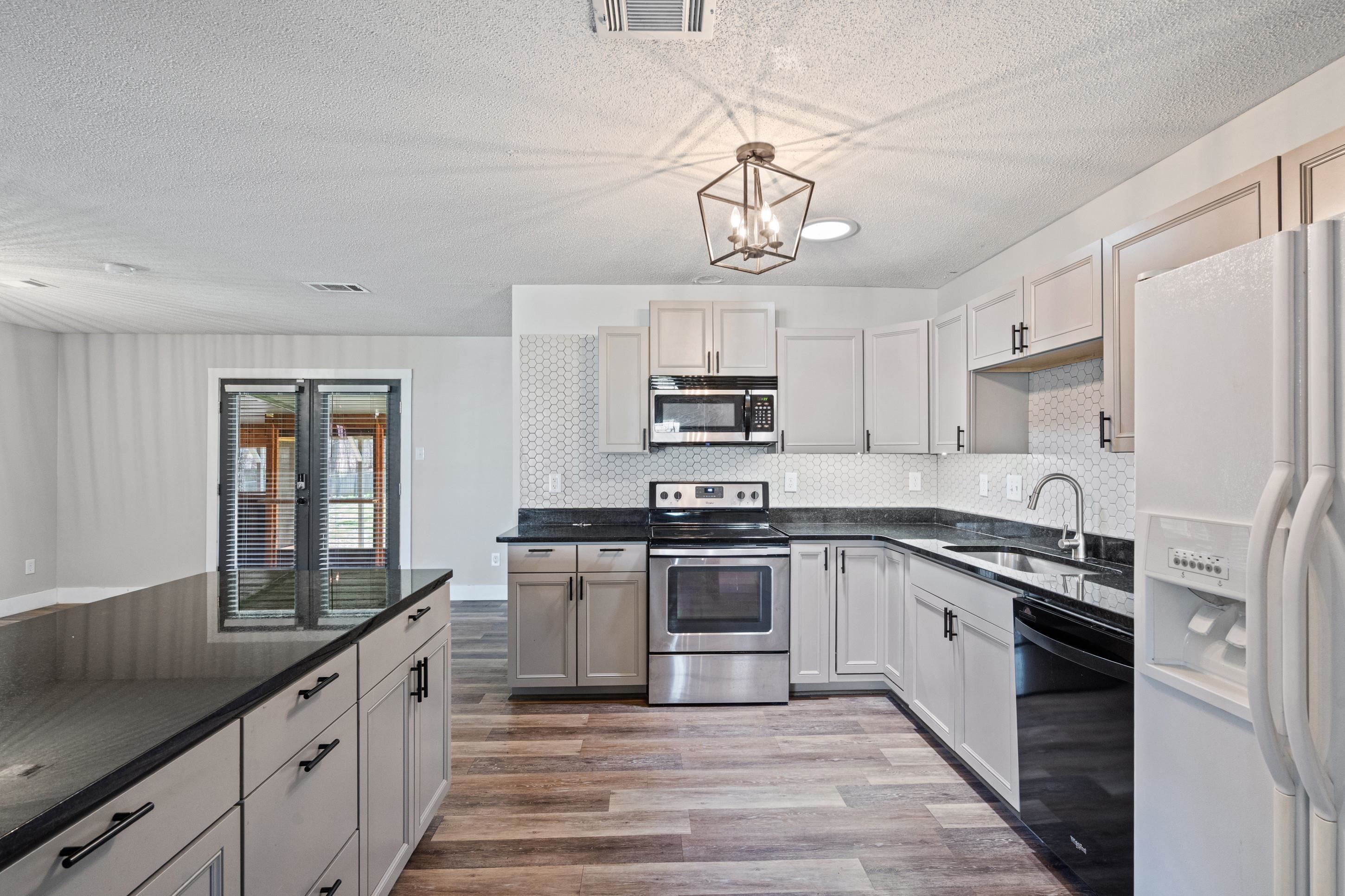 511 Rae Drive Munford, TN 38058 - Photo 6 of 30 Kitchen with stainless steel appliances, light wood-style flooring, decorative backsplash, a textured ceiling, and a chandelier