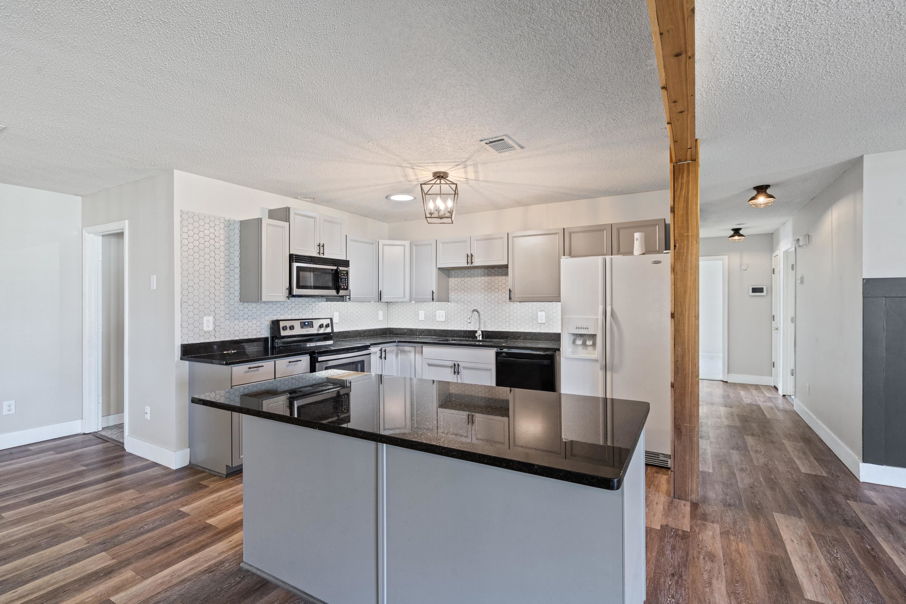 511 Rae Drive Munford, TN 38058 - Photo 7 of 30 Kitchen featuring stainless steel appliances, a kitchen island, dark stone countertops, dark wood-style flooring, and tasteful backsplash