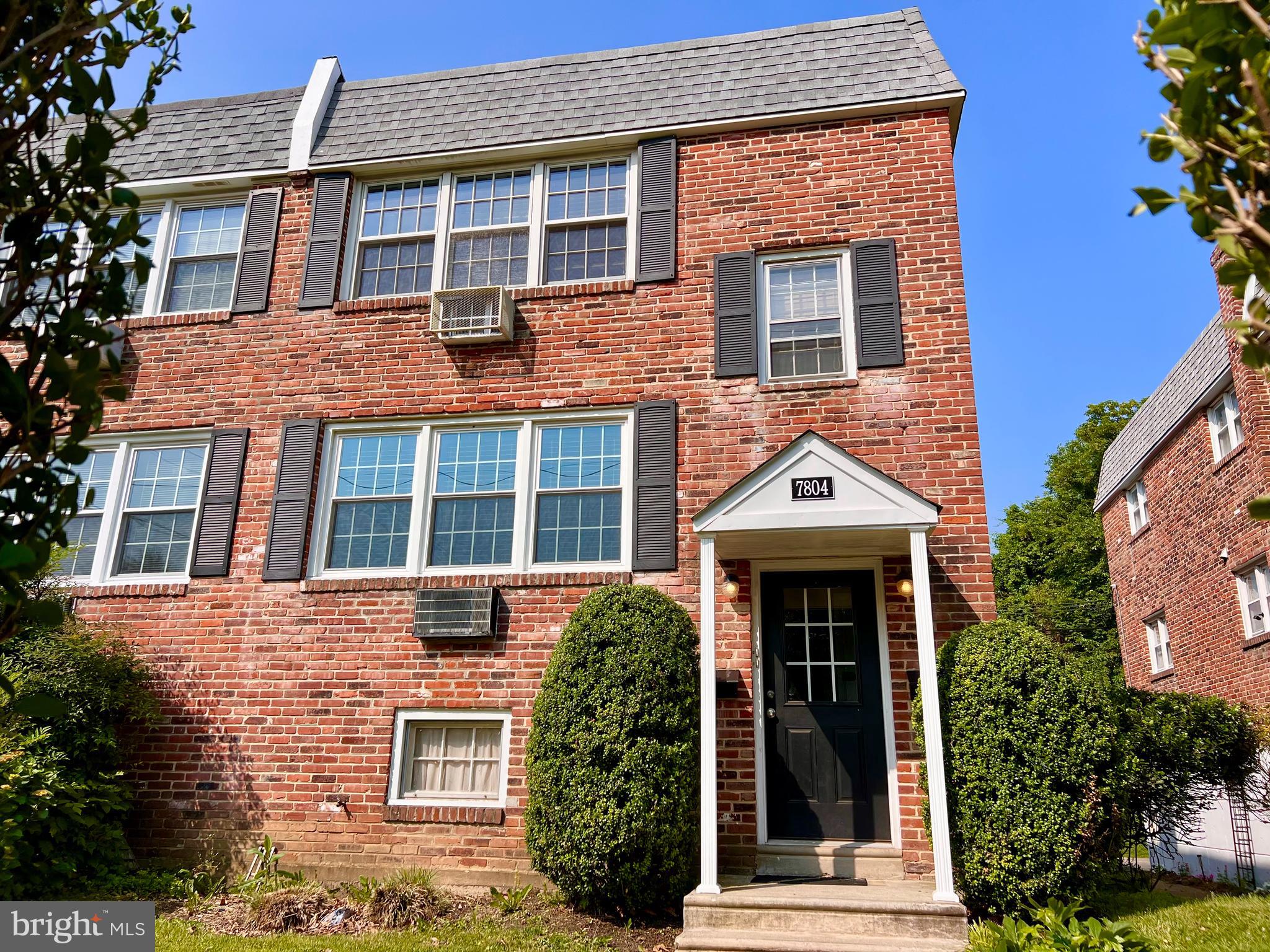 front view of a brick house with a large windows and a potted plant