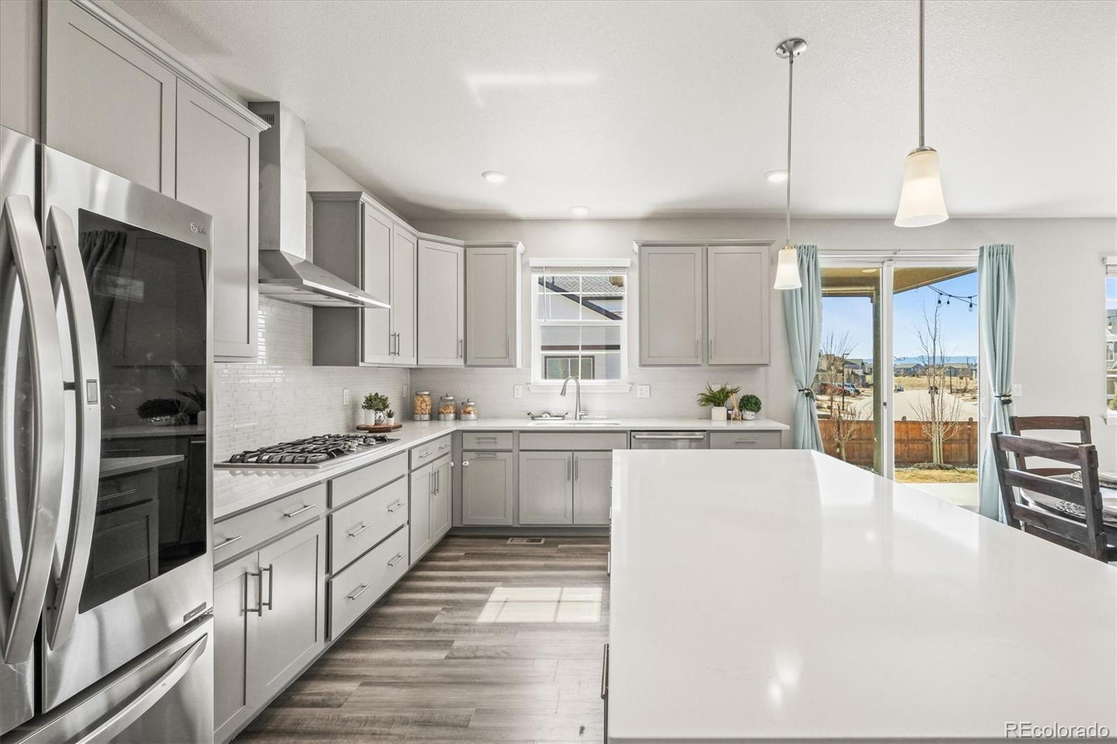 1624 Pinion Wing Circle Castle Rock, CO 80108 - Photo 12 of 47 a large kitchen with stainless steel appliances kitchen island a large counter top a stove a refrigerator cabinets and living room view