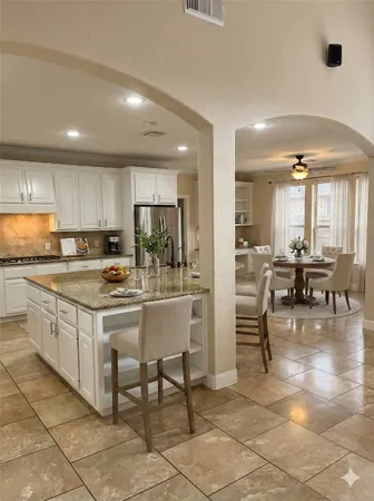a kitchen with stainless steel appliances a stove a sink a oven a dining table and chairs