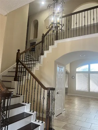 a view of staircase with railing and a chandelier