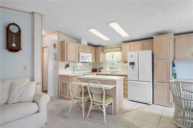 a kitchen with stainless steel appliances a refrigerator a stove a sink a dining table and chairs