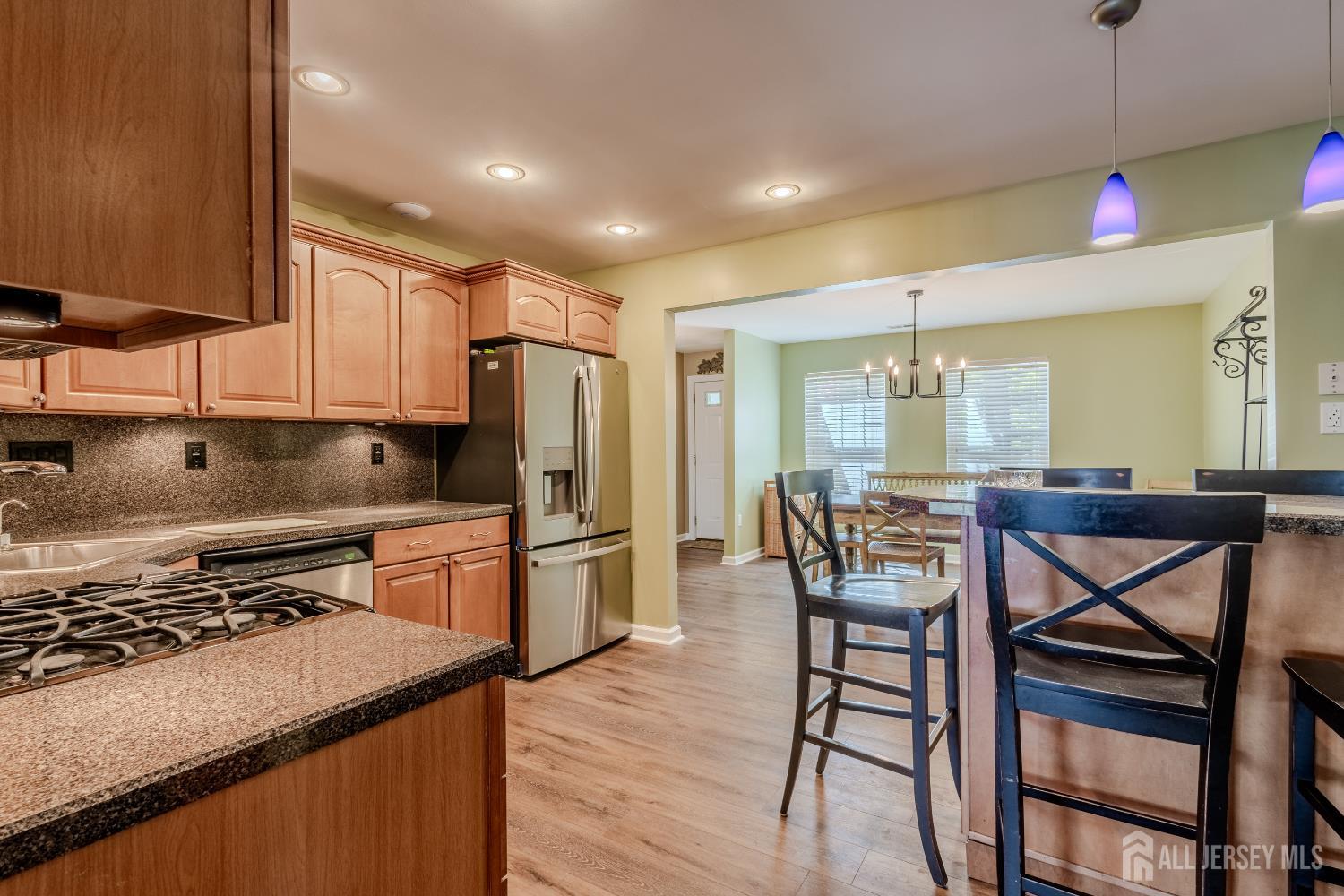 334 Constitution Circle North Brunswick, NJ 08902 - Photo 14 of 42 a kitchen with stainless steel appliances granite countertop a stove top oven a sink a dining table and chairs with wooden floor