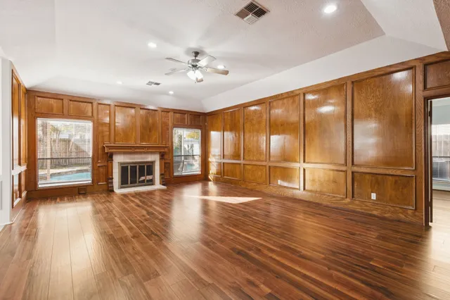 a view of an empty room with wooden floor and a fireplace