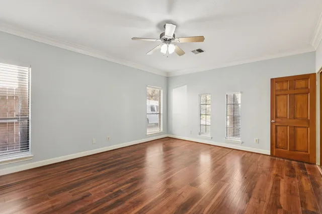 a view of an empty room with wooden floor and window