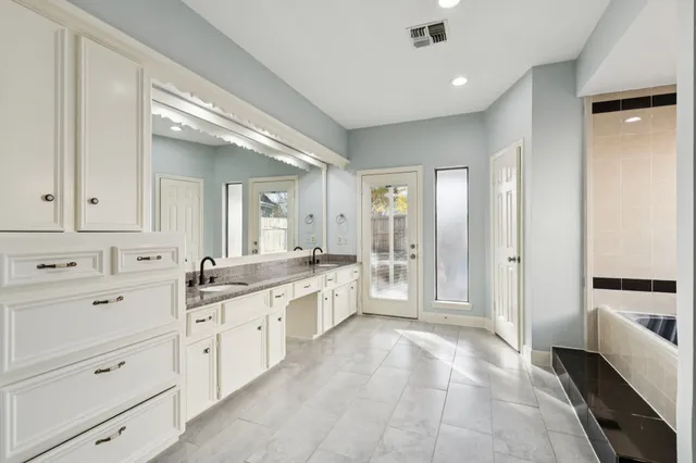 a large white bathroom with a tub sink and mirror