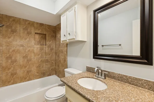 a bathroom with a granite countertop sink toilet a mirror and bathtub