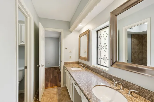 a bathroom with a granite countertop double vanity and a mirror