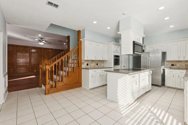 a kitchen with stainless steel appliances kitchen island granite countertop a refrigerator and a stove top oven