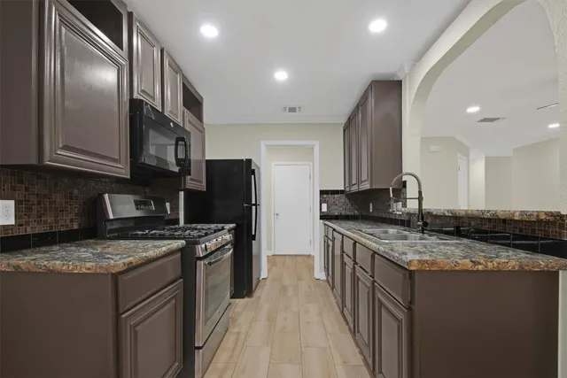 a kitchen with stainless steel appliances granite countertop a stove a sink dishwasher and a refrigerator