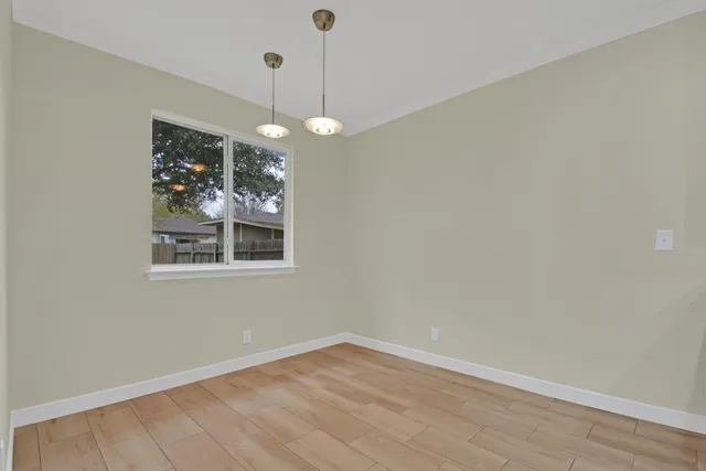 a view of an empty room with window and wooden floor