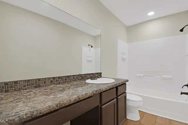 a bathroom with a granite countertop sink a toilet and bathtub