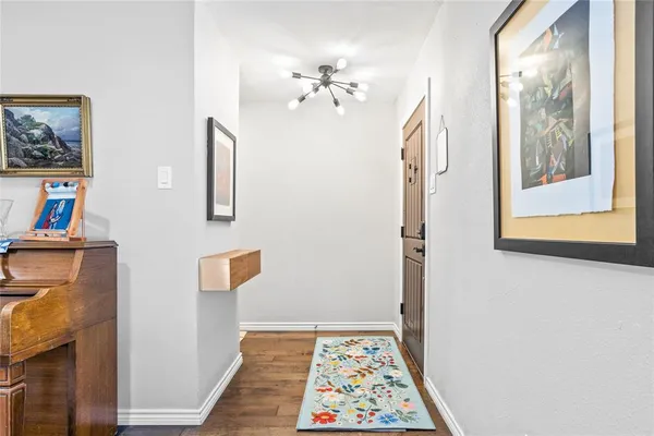 a view of a hallway with wooden floor and a chandelier