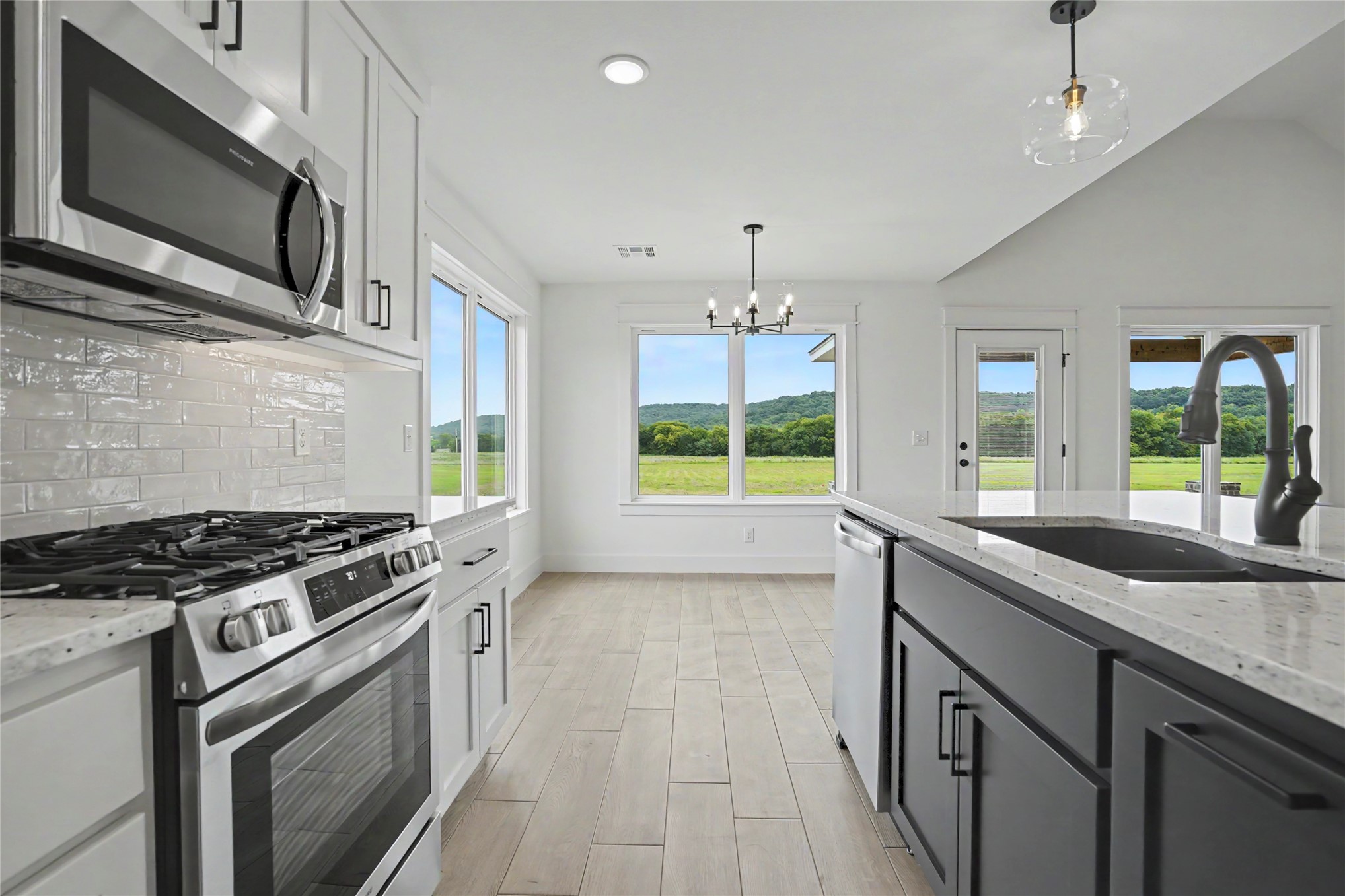 1445 South 4260th Road Chelsea, OK 74016 - Photo 13 of 33 Modern kitchen featuring light wood-finish flooring, white shaker cabinetry, stainless steel appliances, and a tile backsplash