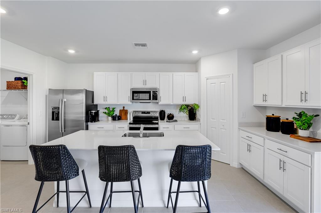 45019 Pipevine Circle Punta Gorda, FL 33982 - Photo 7 of 28 a kitchen with stainless steel appliances kitchen island granite countertop a refrigerator a stove a sink and white cabinets with wooden floor
