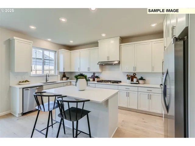 a kitchen with stainless steel appliances a table and chairs in it