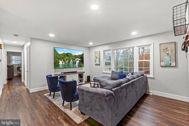 a living room with furniture a large window and wooden floor