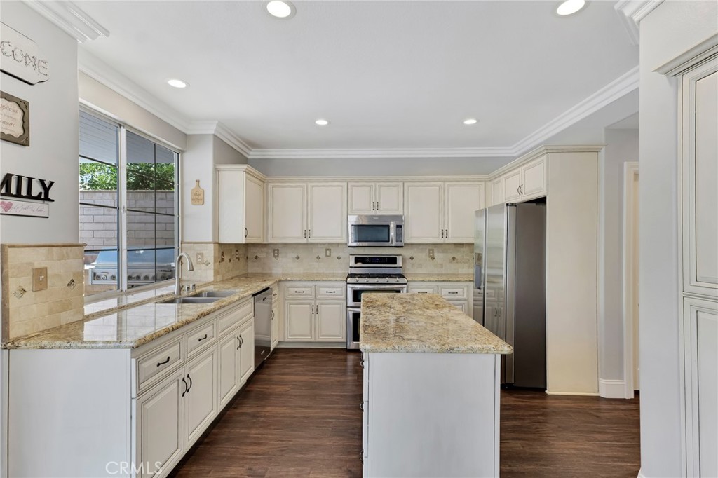 2702 Titania Place Simi Valley, CA 93063 - Photo 11 of 38 a kitchen with stainless steel appliances kitchen island granite countertop a refrigerator a sink dishwasher a stove and white countertops with wooden floor