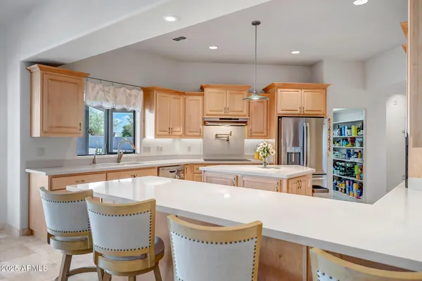 a kitchen with stainless steel appliances granite countertop a stove a sink dishwasher and a dining table with cabinets