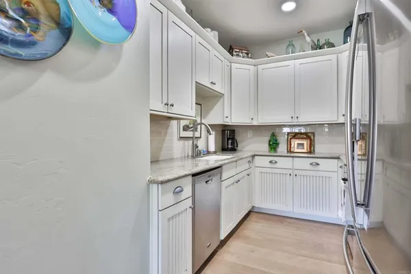 a kitchen with granite countertop a sink stainless steel appliances and white cabinets
