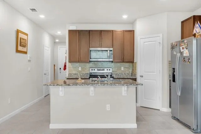 a kitchen with stainless steel appliances granite countertop a stove a refrigerator a sink and dishwasher