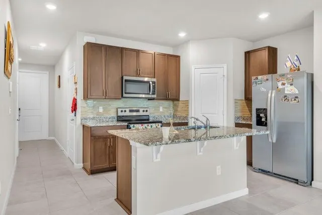 a kitchen with stainless steel appliances granite countertop a refrigerator a stove top oven a sink and dishwasher
