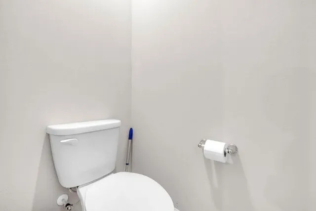 a white toilet sitting next to a white wall
