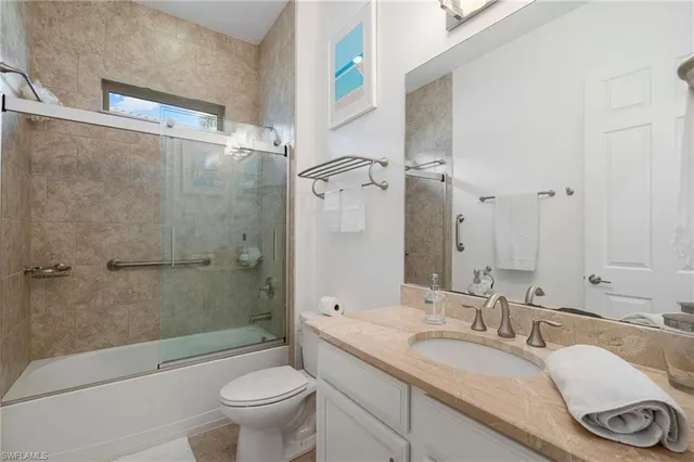 a bathroom with a granite countertop sink a toilet and a large mirror