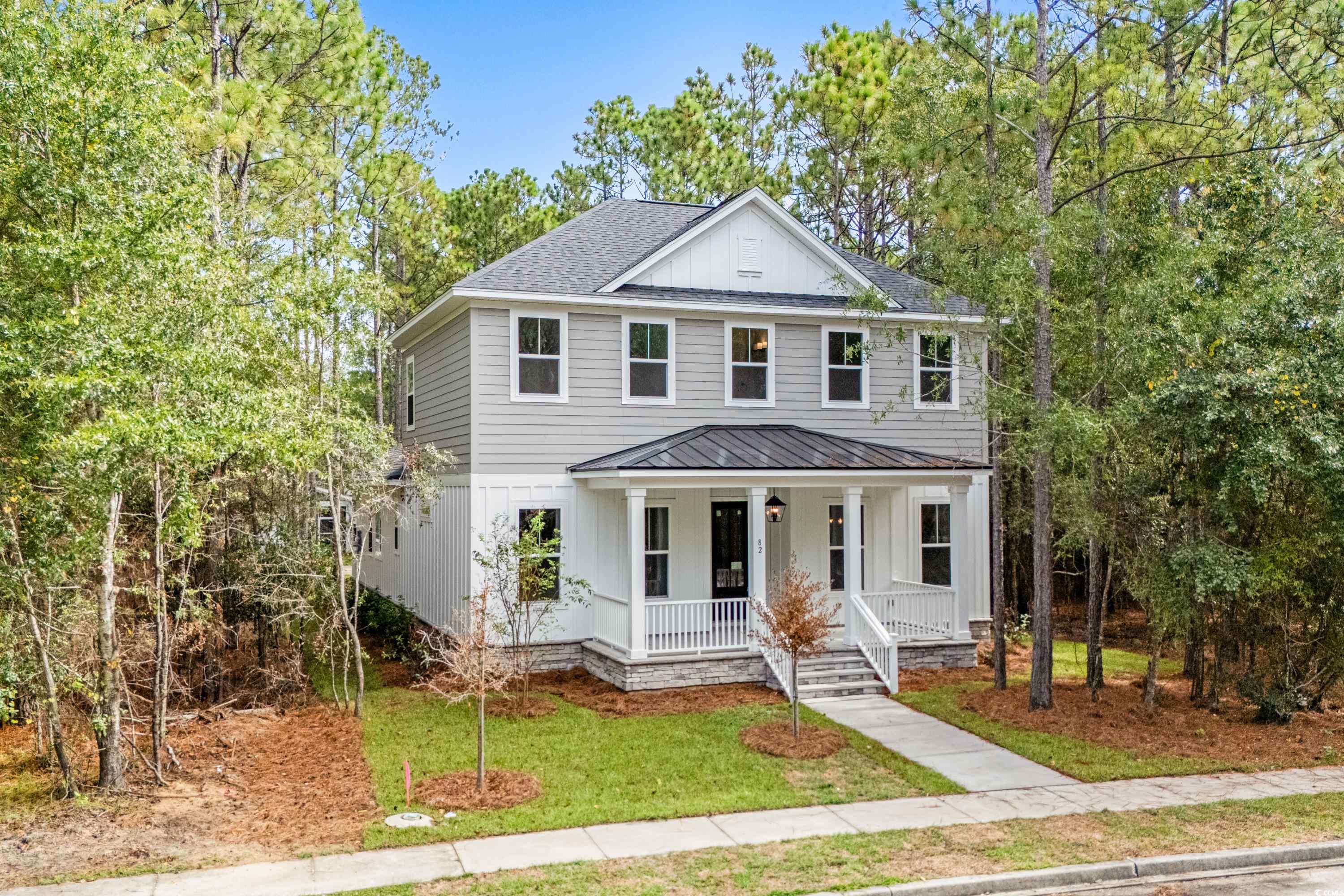View of front of house featuring a porch, a front yard, a shingled roof, a metal roof, and board and batten siding