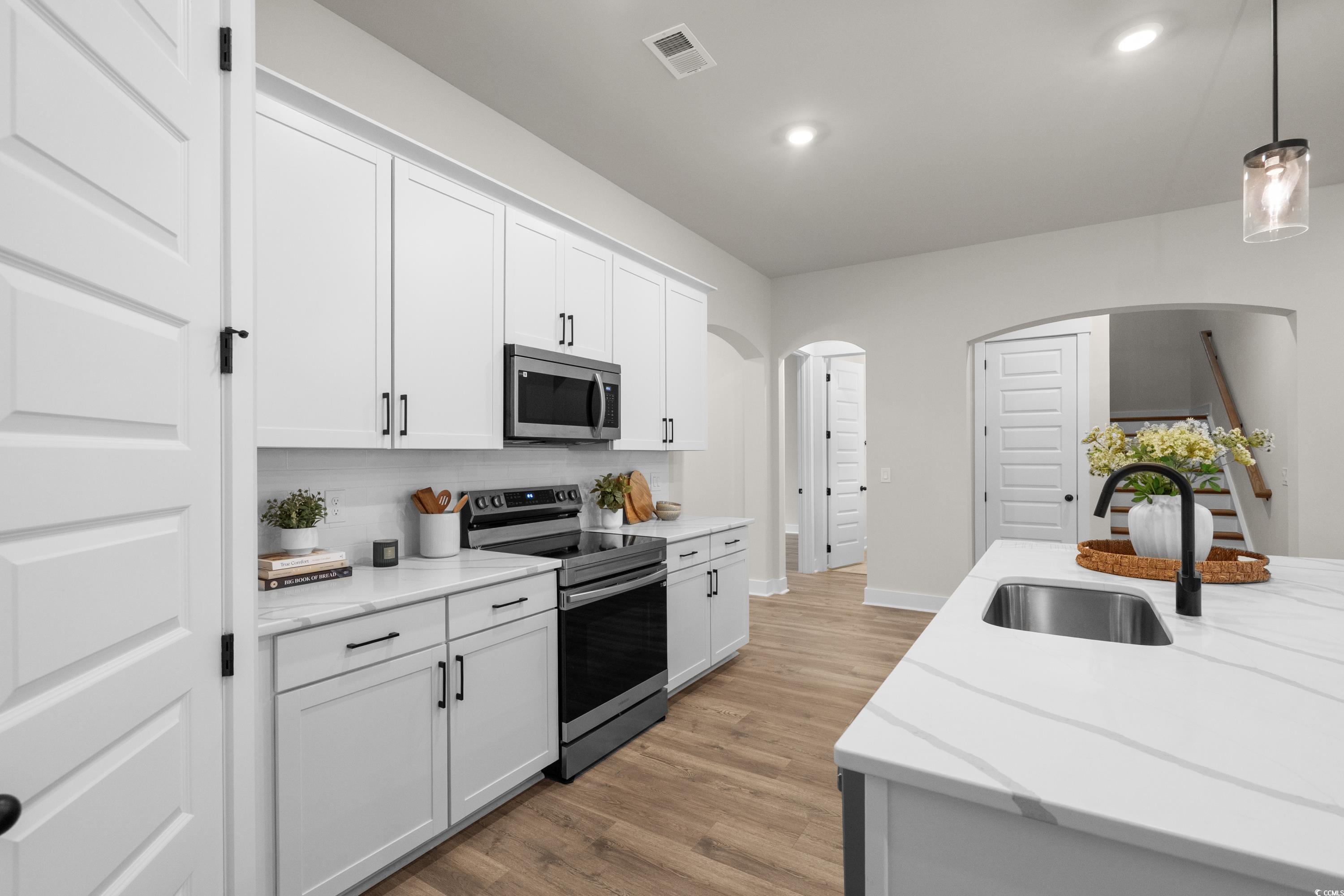 82 Bridge View Road Georgetown, SC 29440 - Photo 11 of 32 Kitchen featuring decorative light fixtures, stainless steel appliances, light wood-type flooring, white cabinetry, and light stone counters