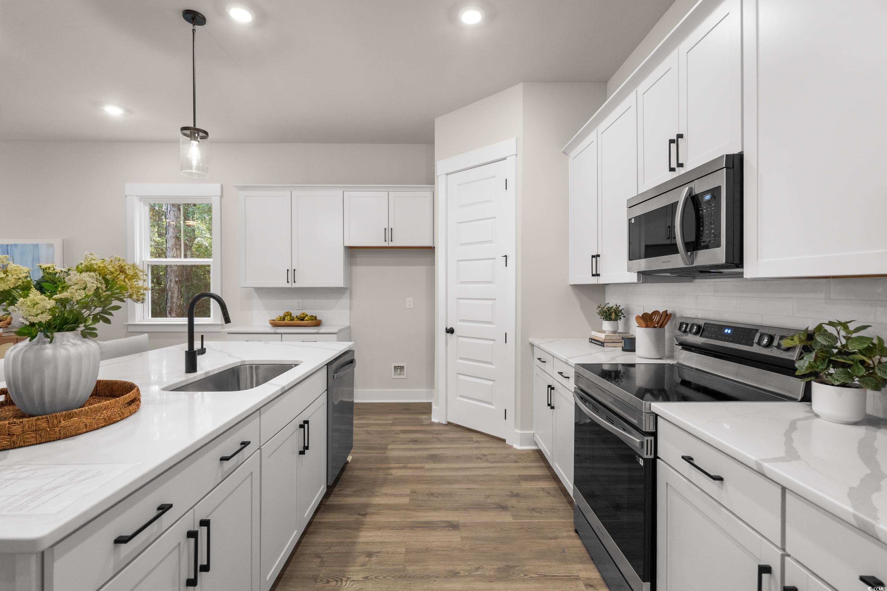 82 Bridge View Road Georgetown, SC 29440 - Photo 10 of 32 Kitchen with stainless steel appliances, white cabinetry, hanging light fixtures, dark wood-style floors, and light stone countertops