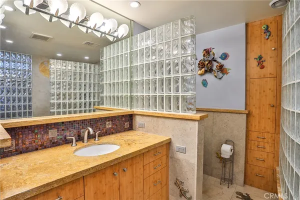 a bathroom with a granite countertop double vanity sink a mirror and shower