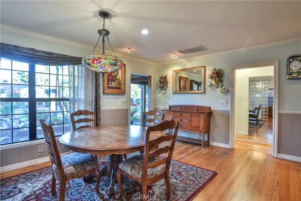 a dining room with wooden floor a chandelier a wooden table and chairs