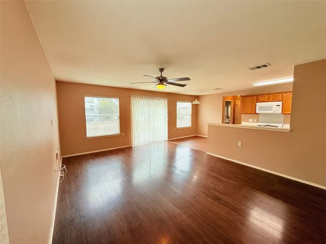a view of an empty room with a window and wooden floor