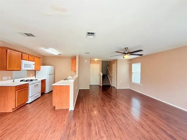 a large kitchen with stainless steel appliances granite countertop a stove a sink dishwasher and a refrigerator with wooden floor